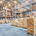 Large industrial warehouse with high racks and cardboard boxes for assessment